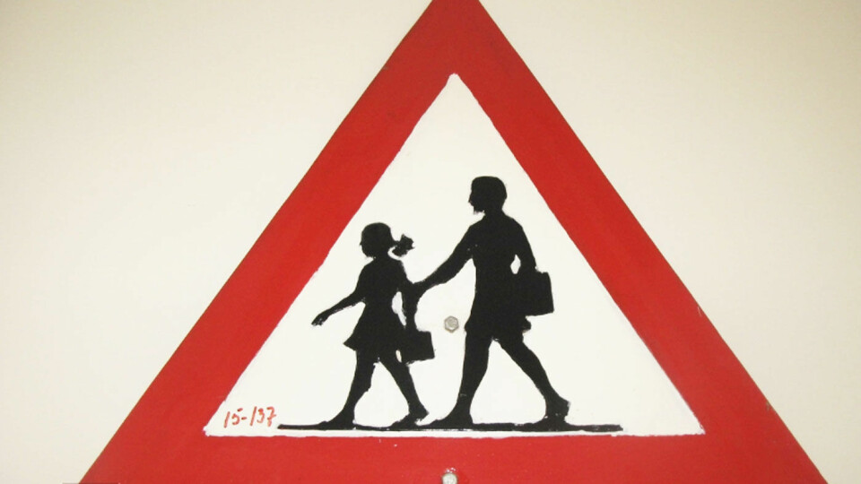 MUSEFLETTER: Fareskiltet som viser barn slik det var, og noen steder fortsatt er, med jente med musefletter og skjørt, og en gutt, begge med ransler. Foto: Vegmuseet