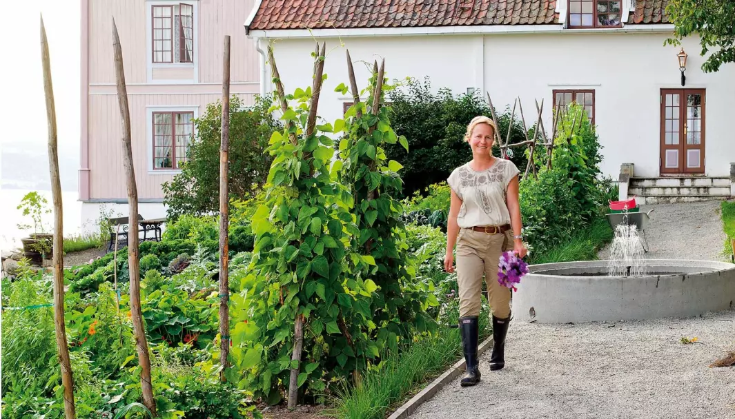 TIL GARDS: Ma­ri­an­ne Ols­søn ønsker gjester velkommen til besøkshagen og gårdsbutikken på Helgøya, fire mil fra Hamar.