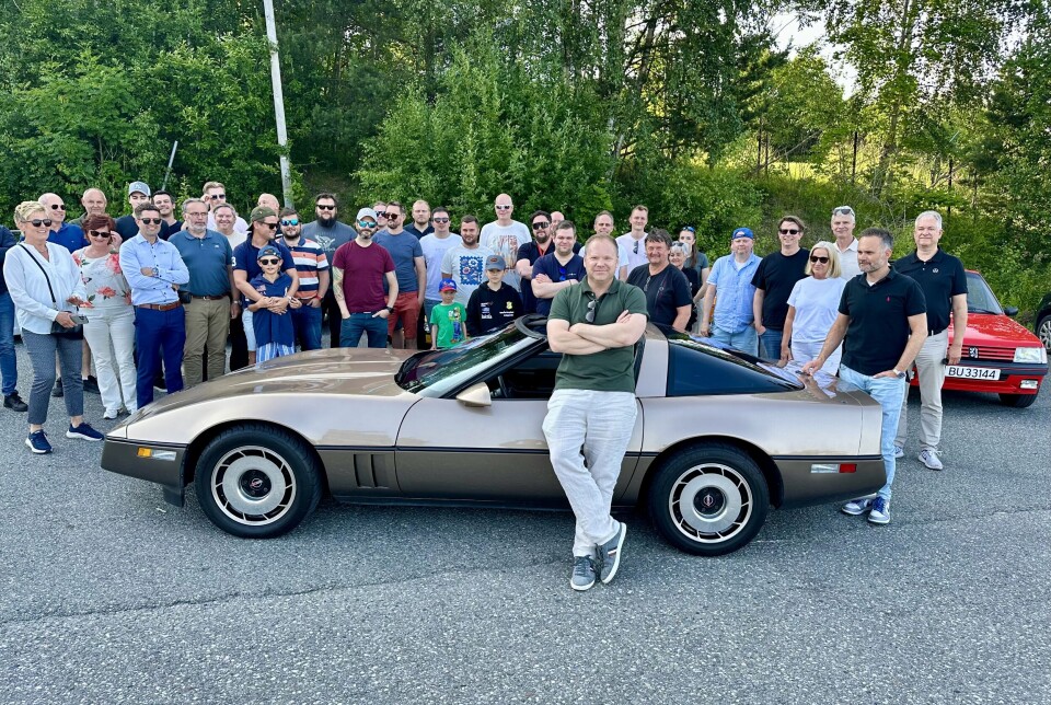 KOLLEGER OG CORVETTE: Christian Lagaard har lurt medarbeidere fra hele organisasjonen til å delta, og ingen angrer ved første stopp-punkt. Bak veggen av kolleger skjuler seg en rekke hobbykjøretøy. I senter for begivenhetene: Lagaards egen Chevrolet Corvette C4.